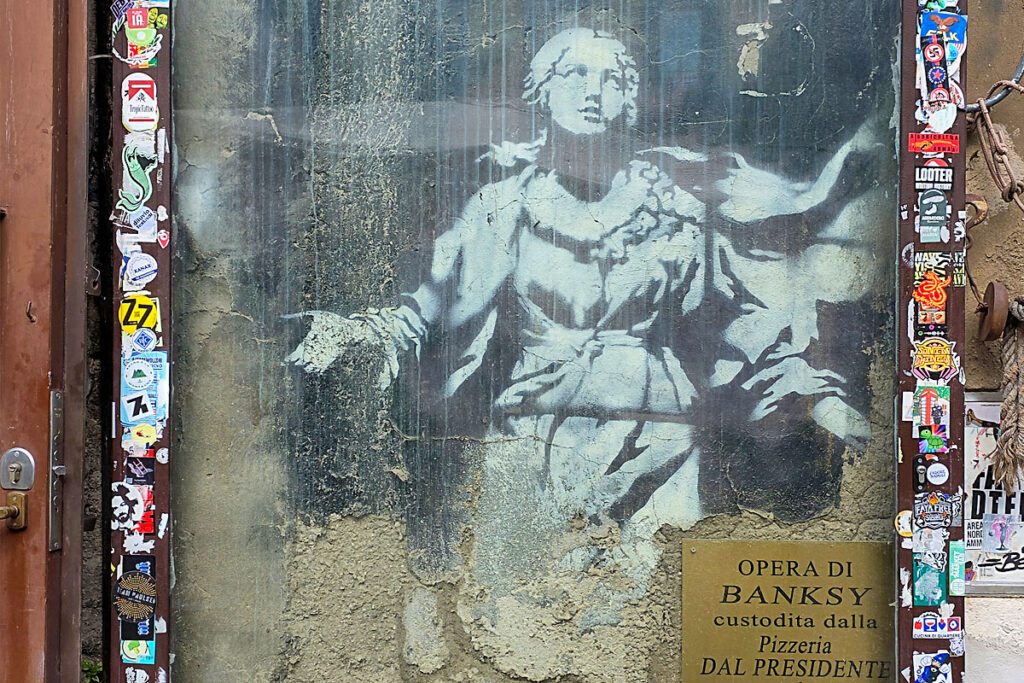 A Banksy Madonna falánál megállsz, majd továbbhaladva Jorit monumentális portréi tűnnek fel — köztük San Gennaro arca, ami egyszerre modern és ikonikus.