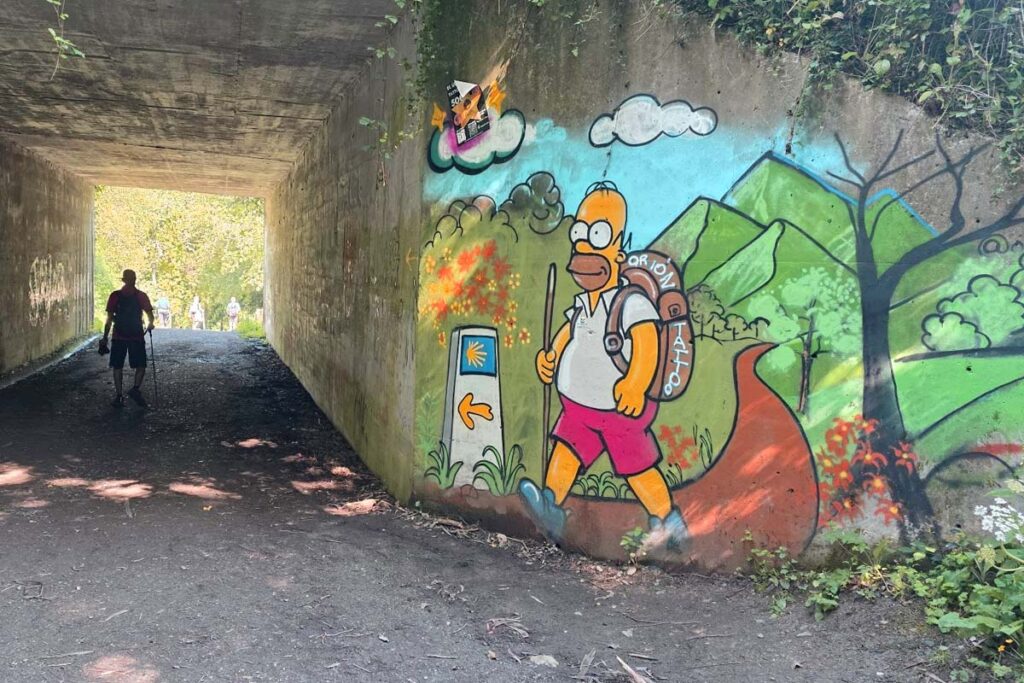 This Simpsons-themed mural featuring Homer Simpson as a pilgrim is located in a pedestrian underpass on the Camino de Santiago route in Boente, Galicia, Spain.